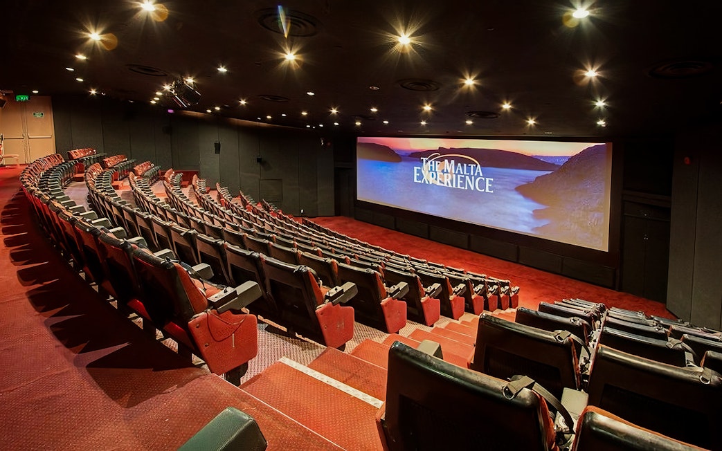 Theater interior for The Malta Experience audio-visual show, featuring a large screen and seating.