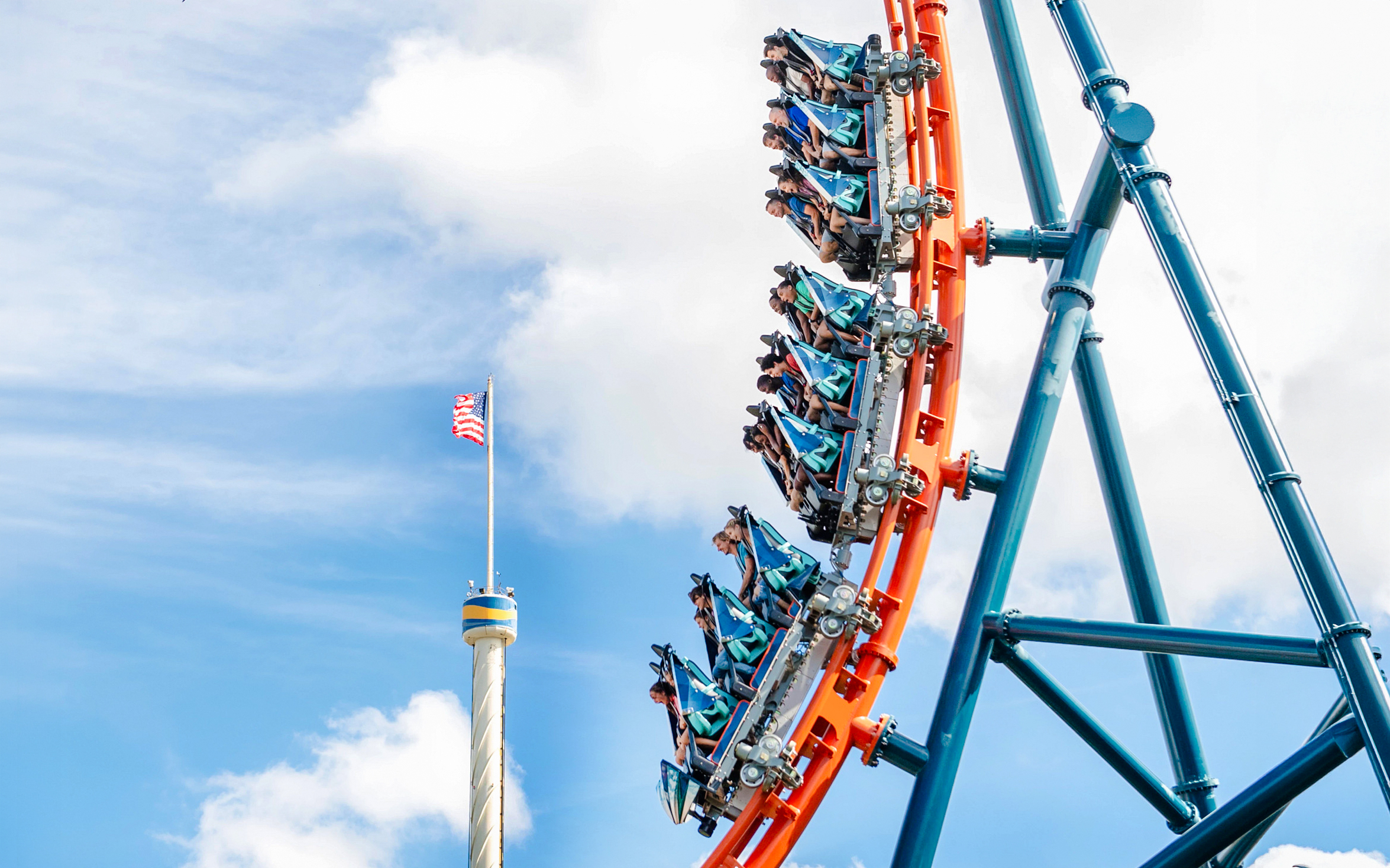 Ice Breaker roller coaster loop at SeaWorld Orlando with riders and American flag in view.