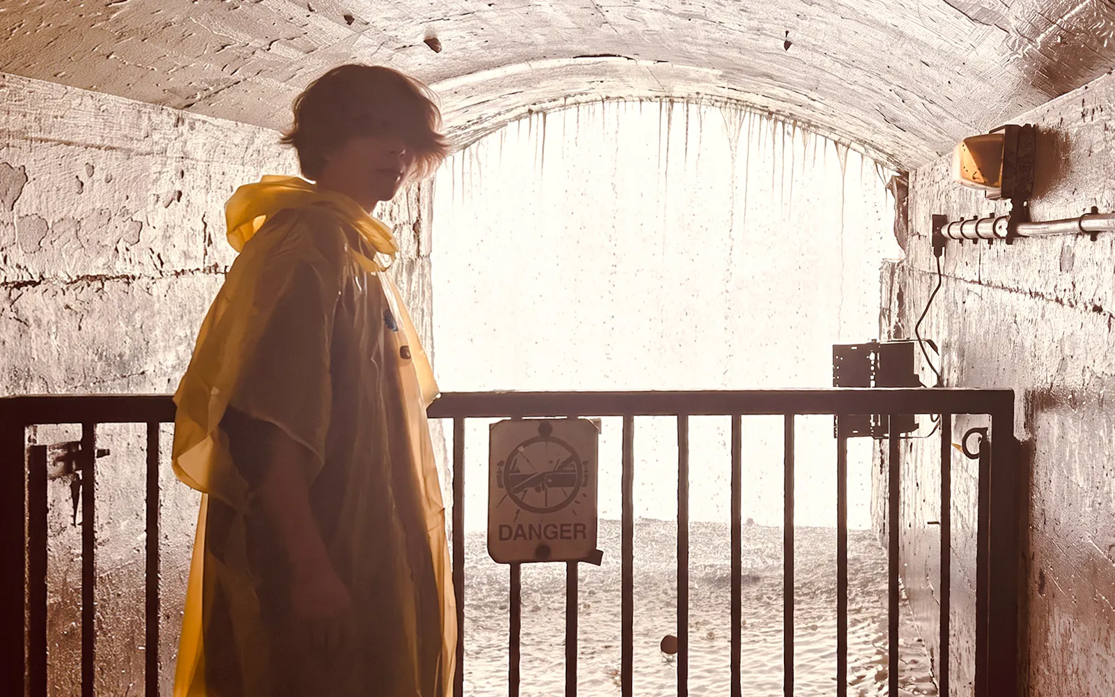 Person in yellow poncho near Niagara Falls tunnel with water cascading behind.