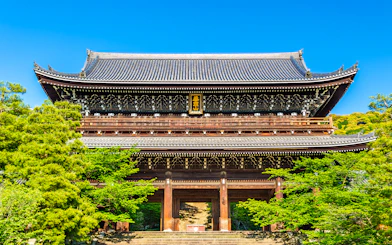 Ancient wooden temple gate surrounded by lush greenery in Kyoto, Japan.