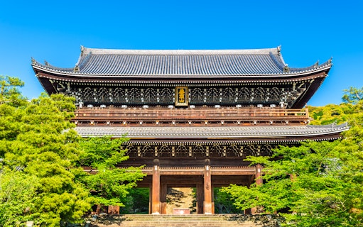 Ancient wooden temple gate surrounded by lush greenery in Kyoto, Japan.
