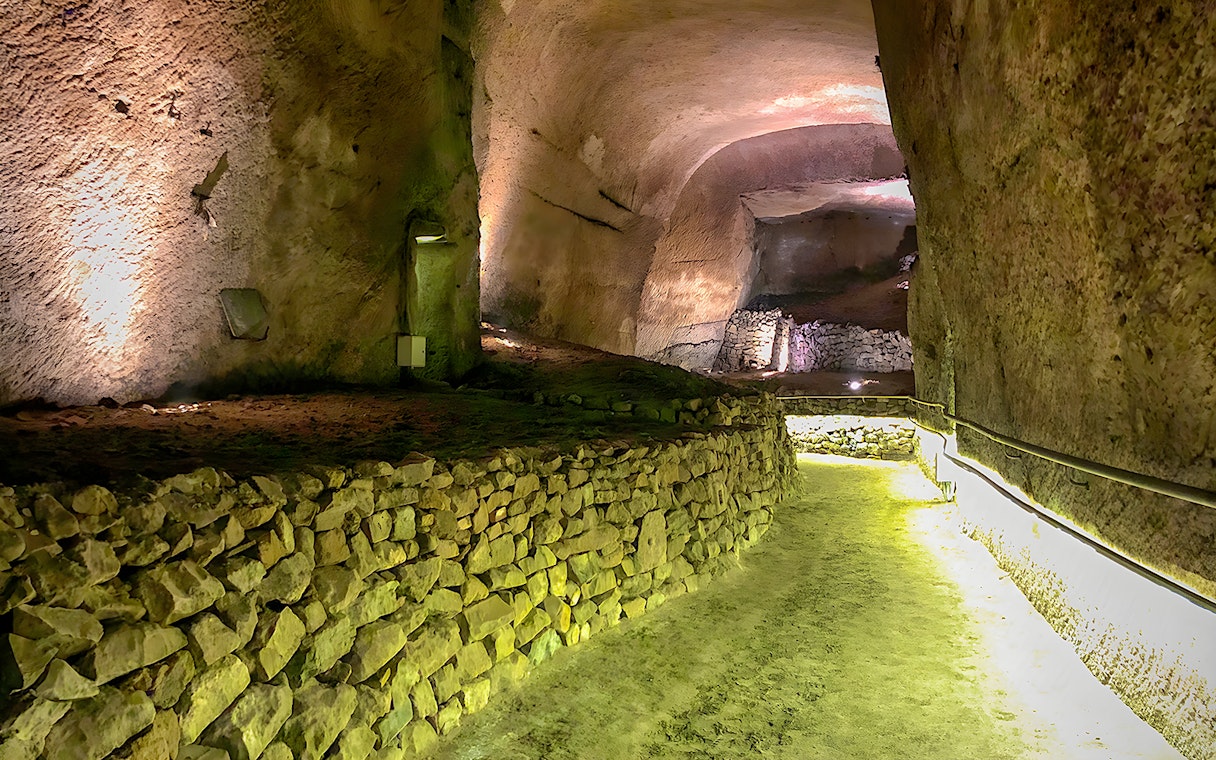 Naples' LAPIS Museum underground passage with ancient stone walls, part of a guided tour.