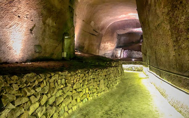 Naples' LAPIS Museum underground passage with ancient stone walls, part of a guided tour.