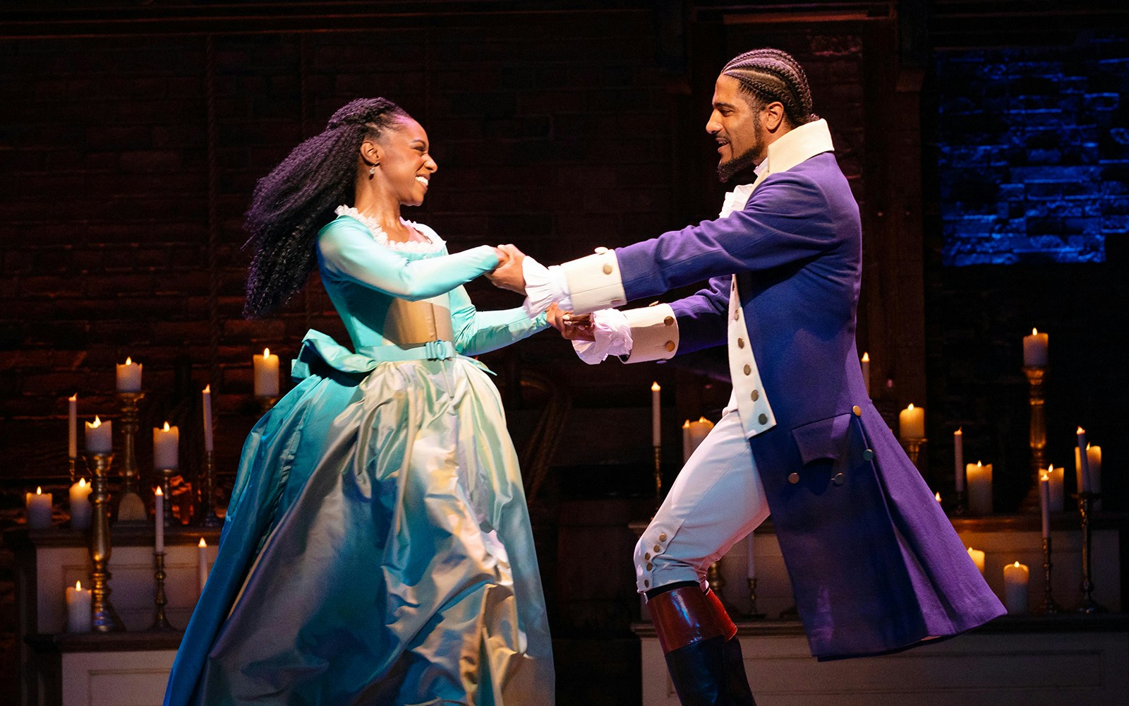 Actors performing a dance scene in the musical Hamilton on stage.