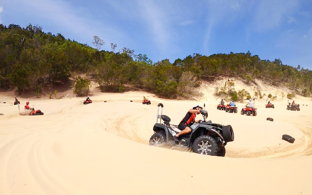 ATV riders navigate sandy dunes at Tangalooma Island Resort.