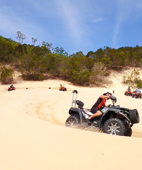 ATV riders navigate sandy dunes at Tangalooma Island Resort.
