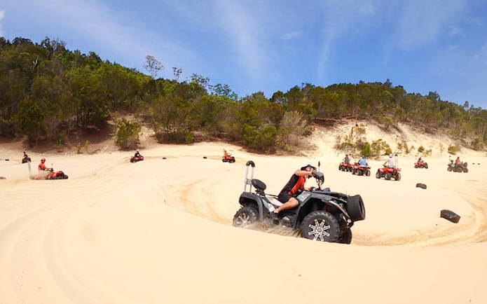 ATV riders navigate sandy dunes at Tangalooma Island Resort.