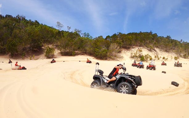 ATV riders navigate sandy dunes at Tangalooma Island Resort.