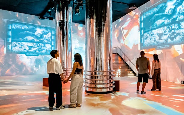 Immersive Jules Verne 200 exhibit with visitors viewing digital oceanic projections.