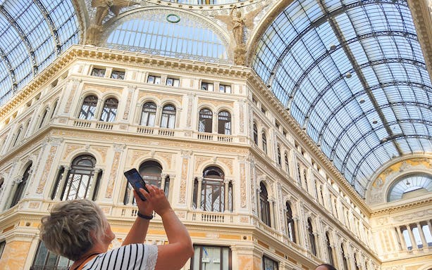 Interior of Galleria Umberto I in Naples with visitor taking a photo.