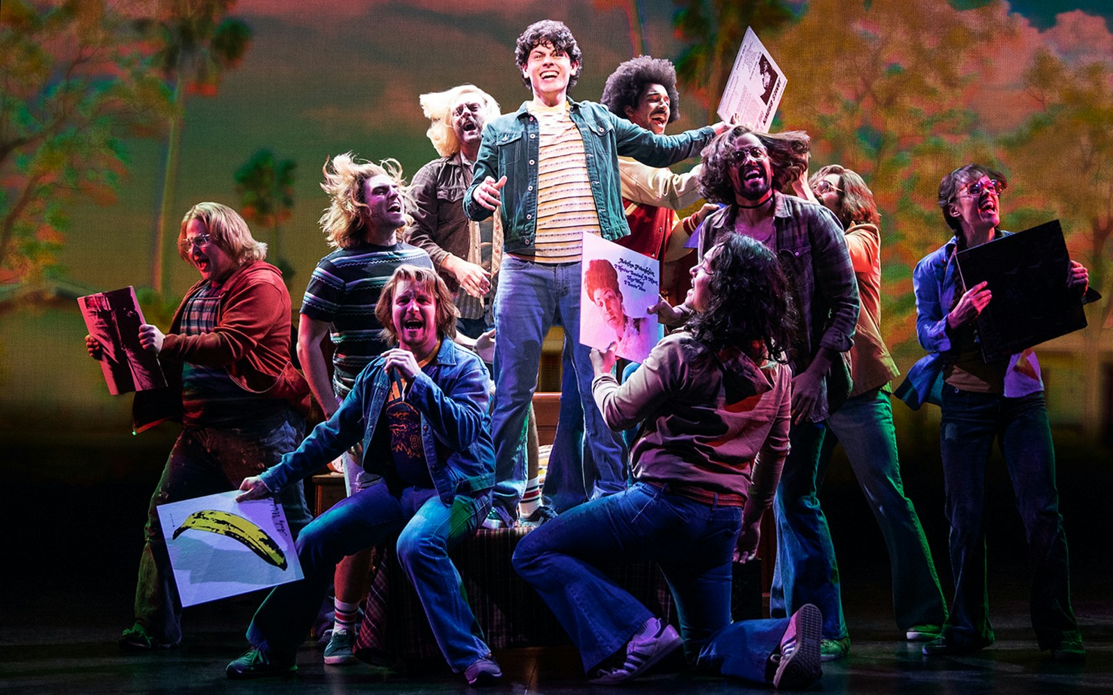 Group of people celebrating with records on stage, related to "Almost Famous" musical.