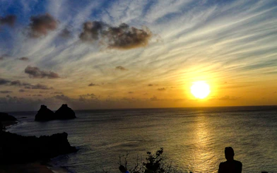 Sunset view over the ocean with silhouetted rocks, Noronha VIP Sunset tour, Sao Paulo.