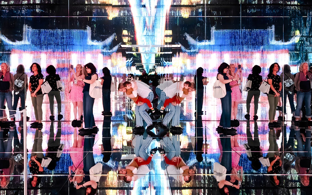 Visitors at Mercer Labs exhibit with mirrored reflections and digital art display.