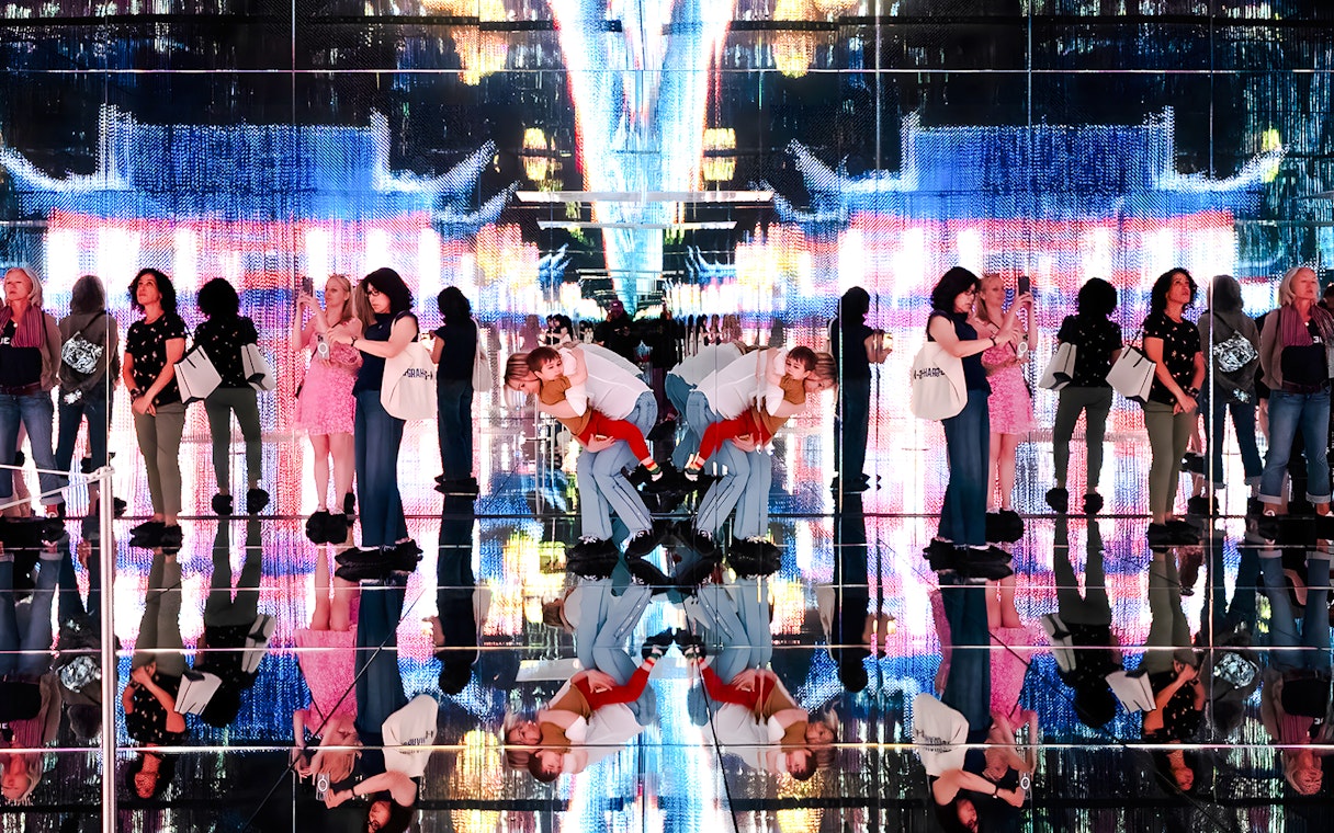 Visitors at Mercer Labs exhibit with mirrored reflections and digital art display.