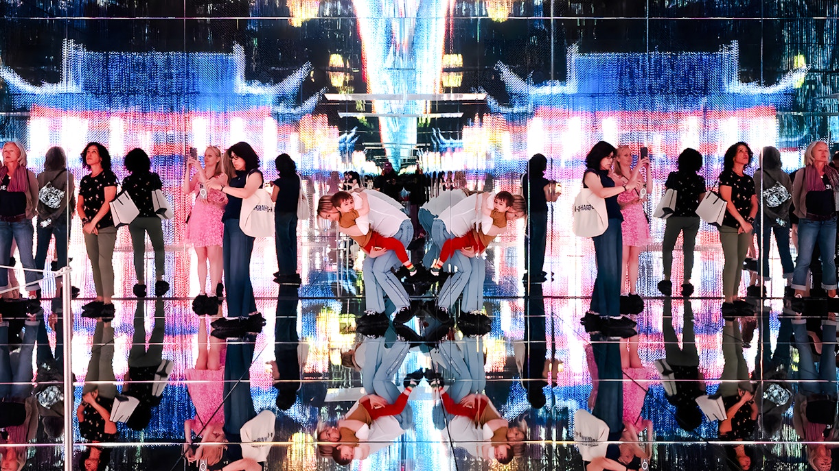 Visitors at Mercer Labs exhibit with mirrored reflections and digital art display.