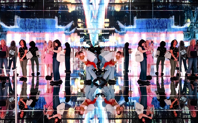 Visitors at Mercer Labs exhibit with mirrored reflections and digital art display.