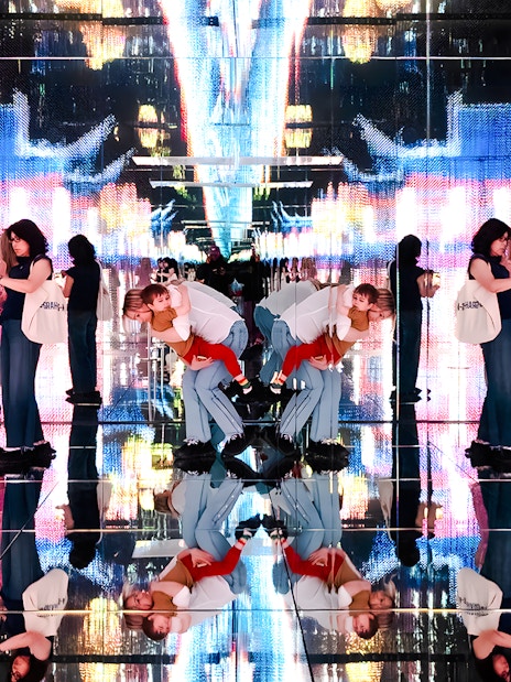 Visitors at Mercer Labs exhibit with mirrored reflections and digital art display.