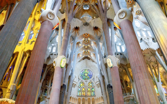 Sagrada Familia interior with stained glass windows and ornate columns in Barcelona.