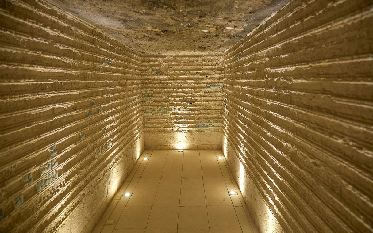Corridor inside the Step Pyramid of Djoser, Saqqara, Egypt, with illuminated stone walls.