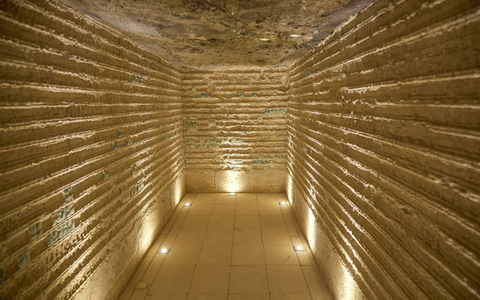 Corridor inside the Step Pyramid of Djoser, Saqqara, Egypt, with illuminated stone walls.
