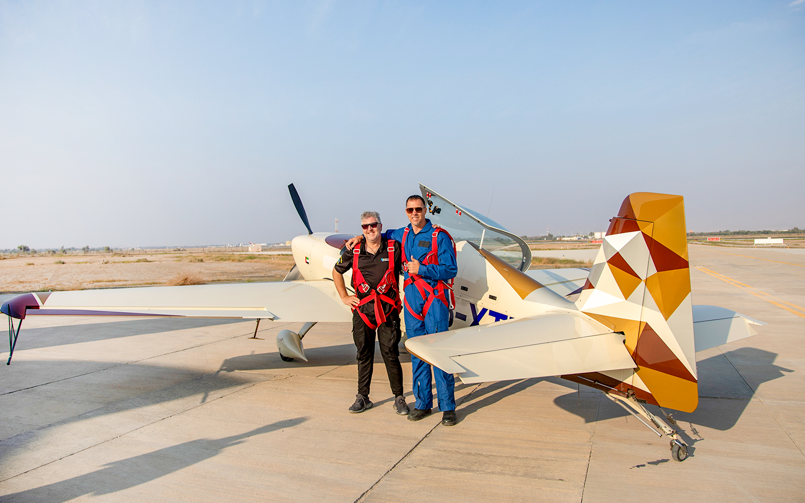 Pilot and passenger posing beside aerobatic plane after GFORCE Aerobatic Passenger Experience.