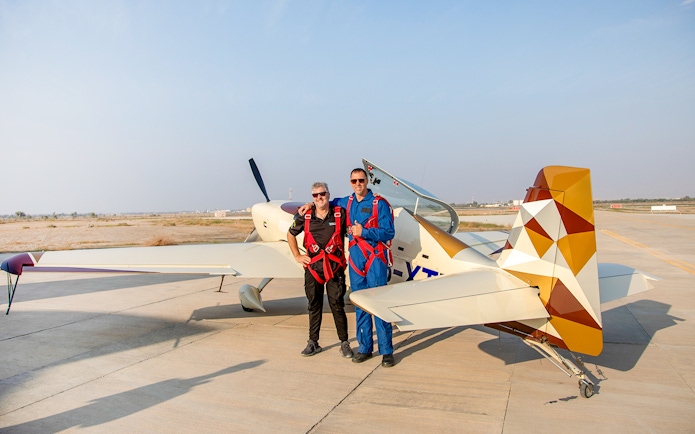 Pilot and passenger posing beside aerobatic plane after GFORCE Aerobatic Passenger Experience.