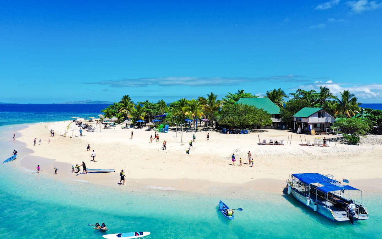 South Sea Cruise boat near tropical island beach with visitors, Fiji.
