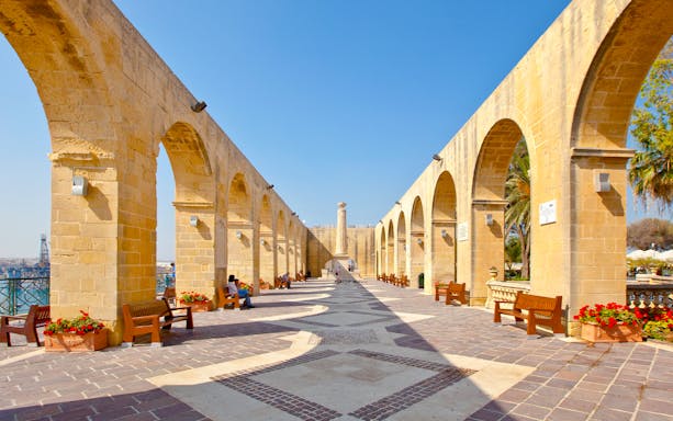 Upper Barrakka Gardens arches in Valletta, Malta, with benches and flowers.