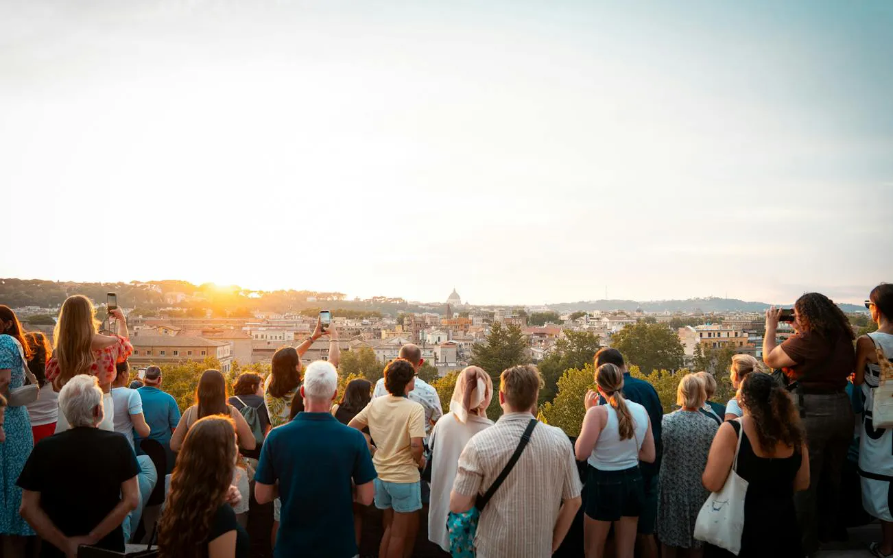 Tourists enjoying a sunset view over Rome from a panoramic vantage point.