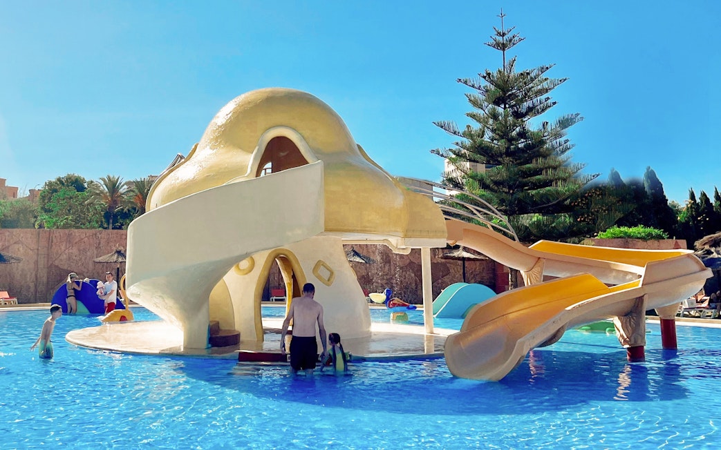Mushroom-shaped water slide at Aqualand Torremolinos with children playing in the pool.