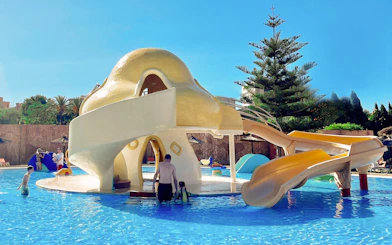 Mushroom-shaped water slide at Aqualand Torremolinos with children playing in the pool.