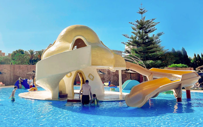 Mushroom-shaped water slide at Aqualand Torremolinos with children playing in the pool.