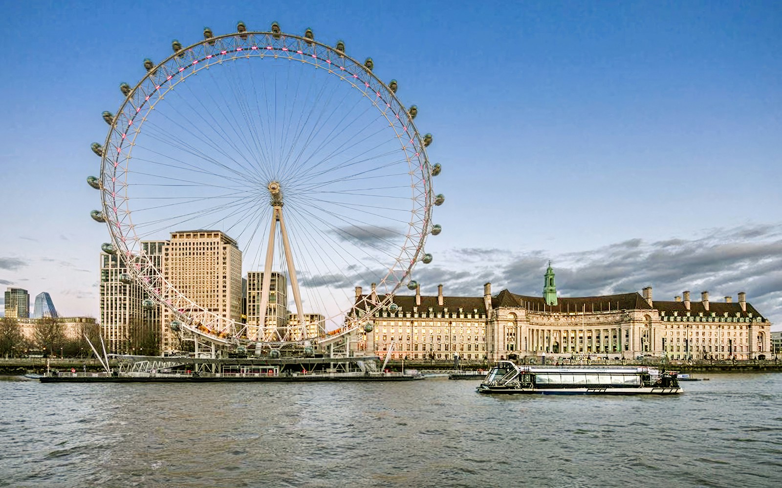 Evening cruise on the Thames with view of the London Eye and riverside buildings.