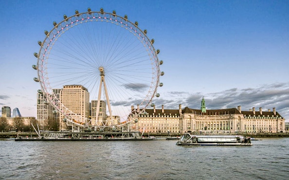 Evening cruise on the Thames with view of the London Eye and riverside buildings.