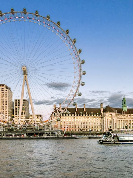 Evening cruise on the Thames with view of the London Eye and riverside buildings.