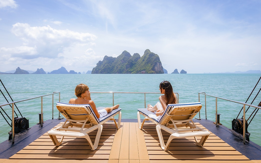 Guests relaxing on a deck with ocean view and distant islands.