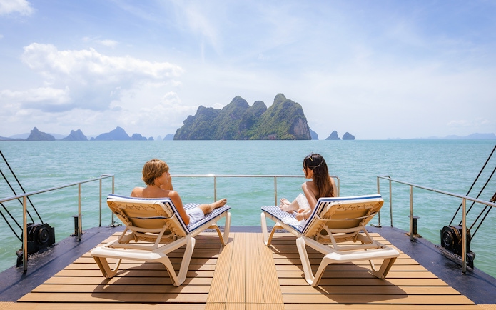 Guests relaxing on a deck with ocean view and distant islands.