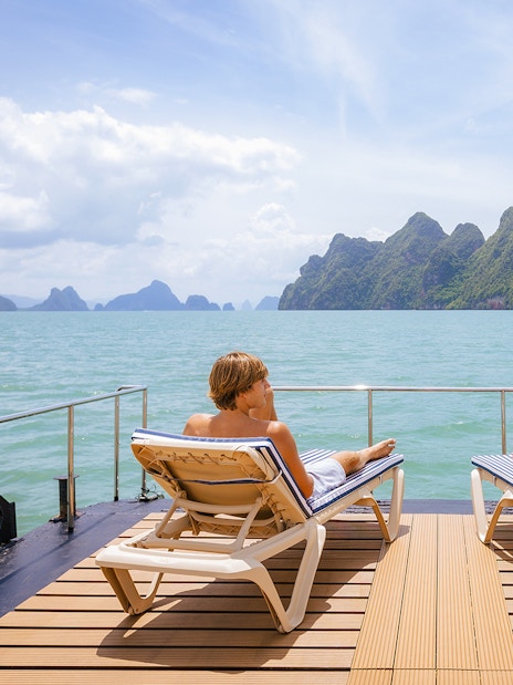 Guests relaxing on a deck with ocean view and distant islands.