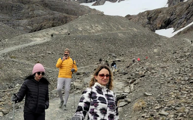 Tourists hiking on Ushuaia Martial Glacier trail with rocky terrain and snow patches.