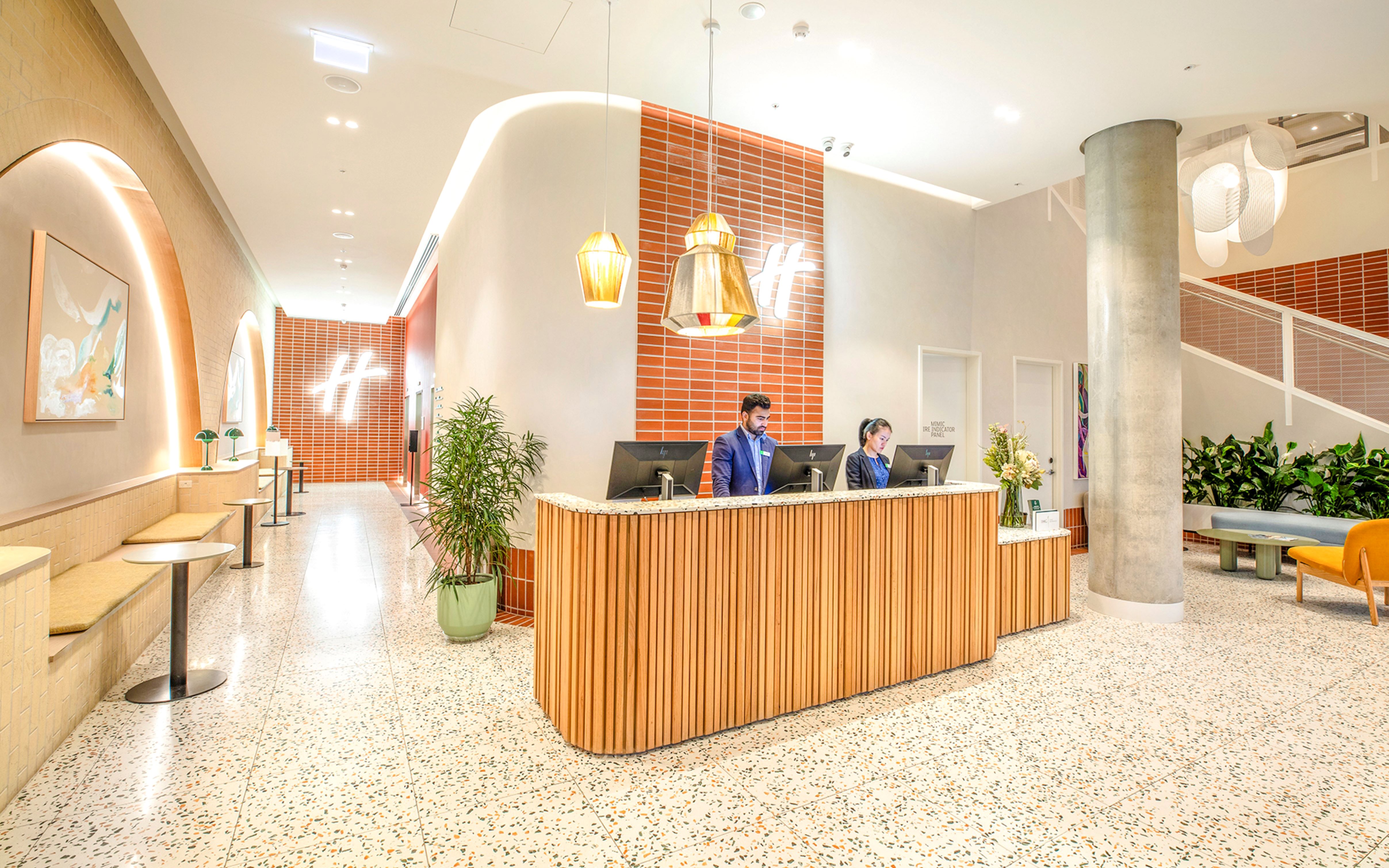 Reception area at Holiday Inn & Suites Geelong with modern decor and staff at the front desk.