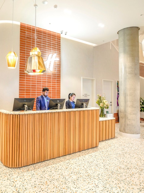 Reception area at Holiday Inn & Suites Geelong with modern decor and staff at the front desk.