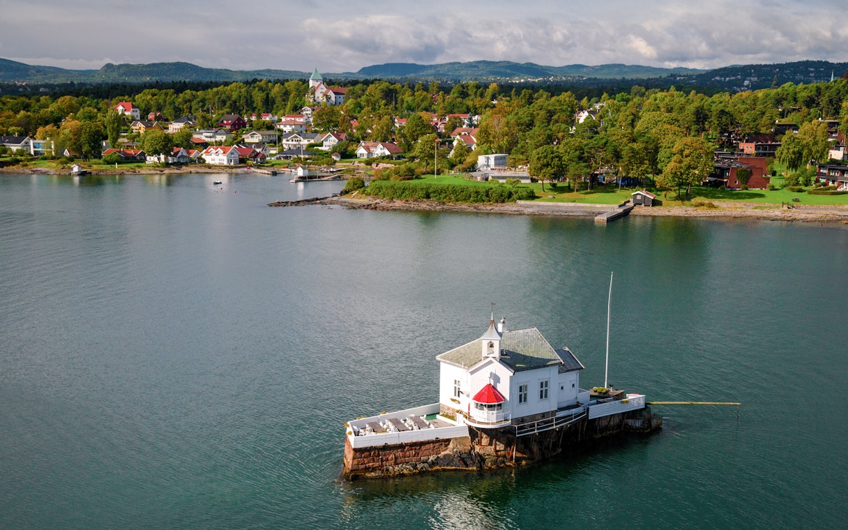 Oslo Fjord lighthouse with scenic coastal village backdrop.