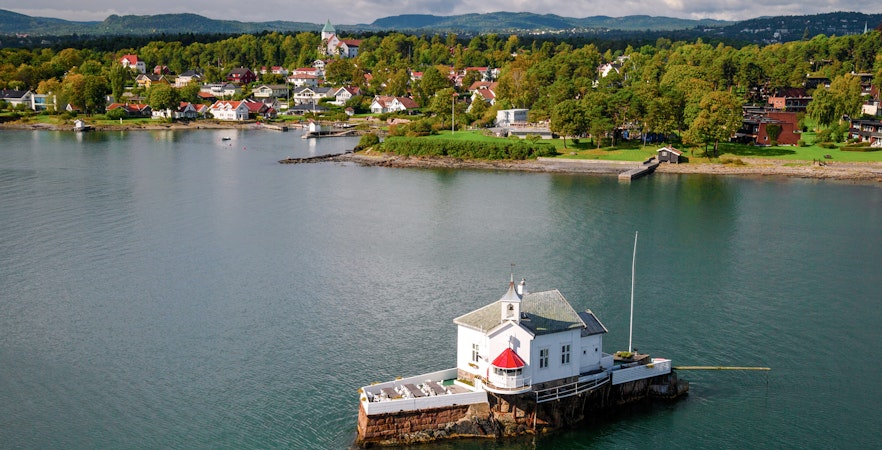 Oslo Fjord lighthouse with scenic coastal village backdrop.