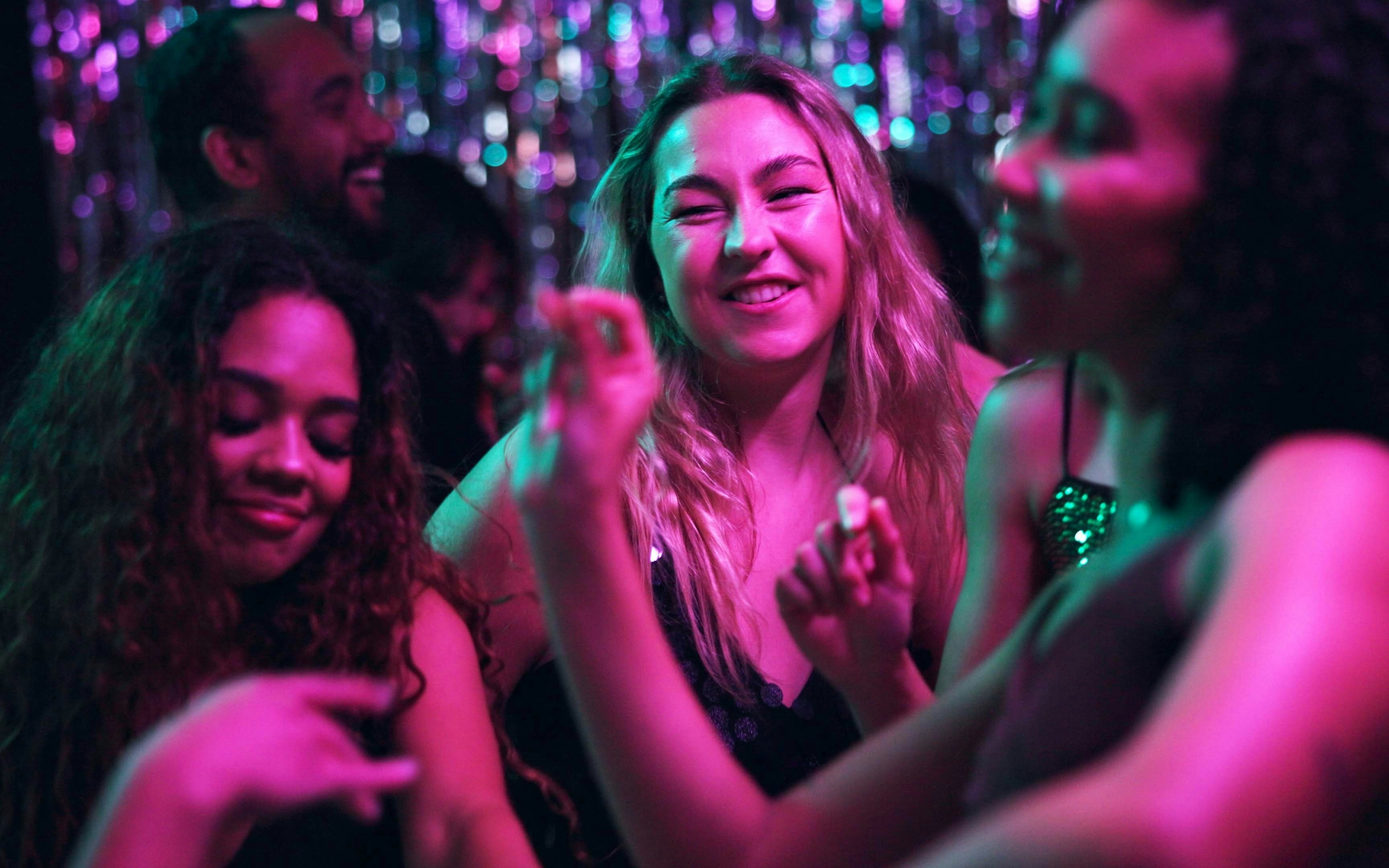 Women enjoying a disco event with colorful lights in the background.