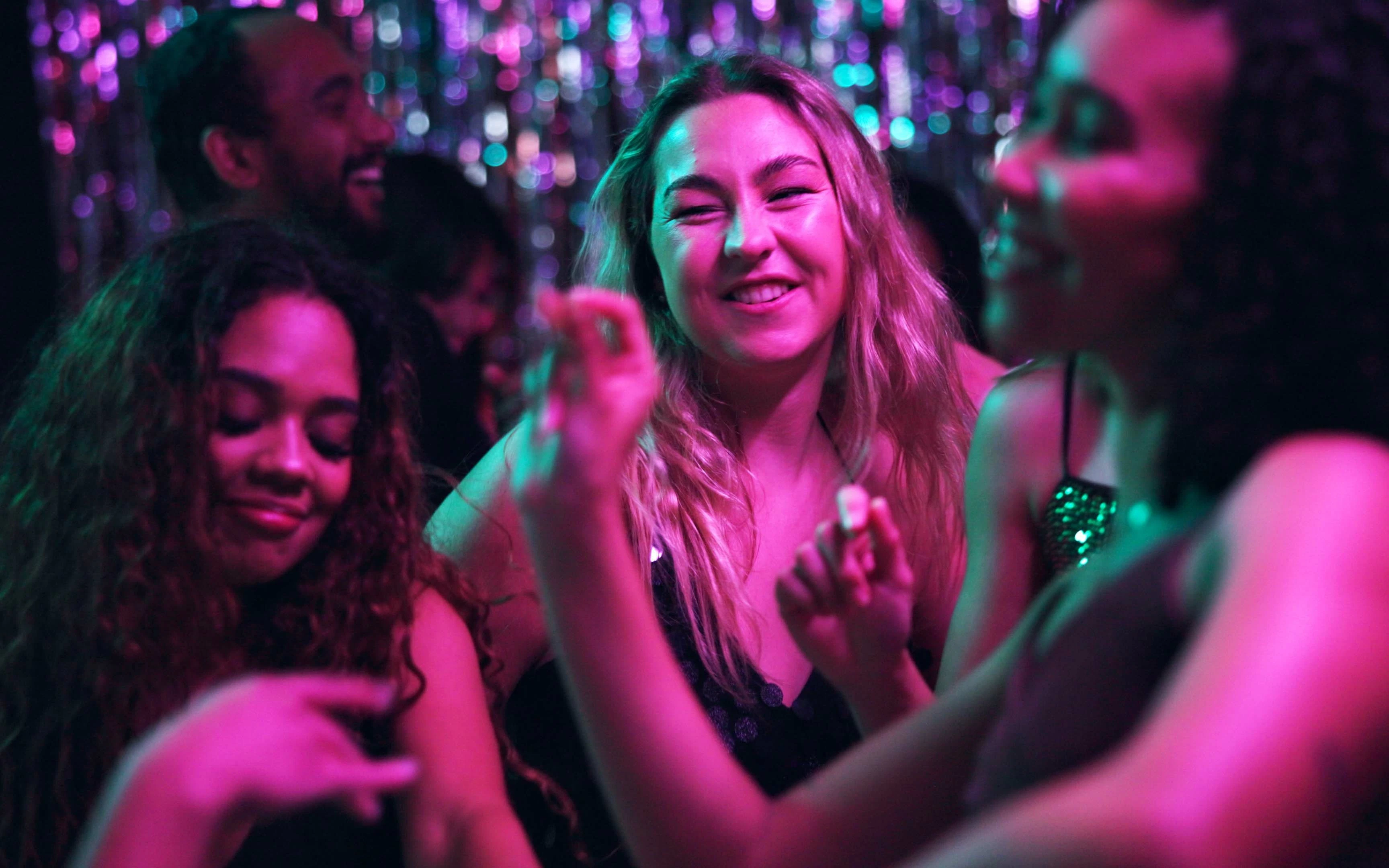 Women enjoying a disco event with colorful lights in the background.