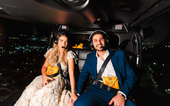 Couple enjoying a nighttime helicopter tour over New York City.