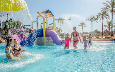 Children playing in the water park area of Aqualand El Arenal with colorful slides.