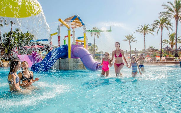 Children playing in the water park area of Aqualand El Arenal with colorful slides.