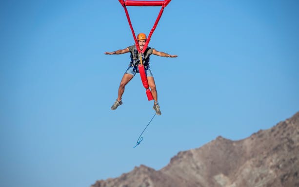 Person ziplining at Hatta Wadi Hub with mountains in the background.