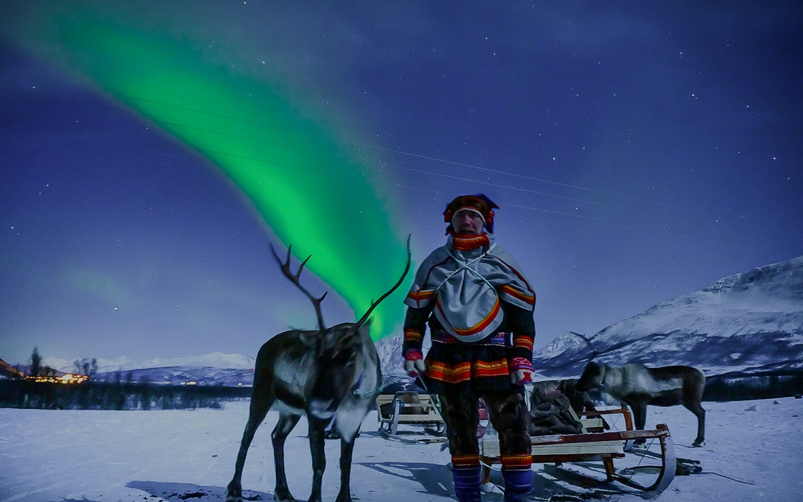 Reindeer sledding under Northern Lights in Tromso, Norway.